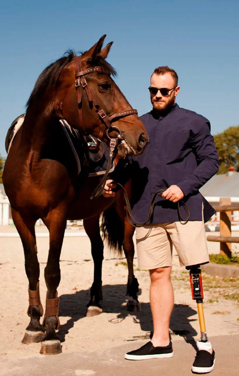 Hombre con gafas de sol junto a un caballo, con prótesis de pierna